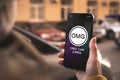 OMG coin cryptocurrency symbol, logo. Business and financial concept. Hand with smartphone, screen with crypto icon