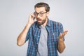 OMG! Happy amazed young man in checkered shirt talking on cell phone on grey background. Isolated Royalty Free Stock Photo