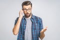 OMG! Happy amazed young man in checkered shirt talking on cell phone on grey background. Isolated Royalty Free Stock Photo