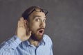 Curious man listening with hand at ear eavesdropping on a shocking gossip at work