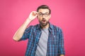 OMG! It`s incredible! Portrait of handsome young man in glasses looking at camera while standing against pink background. Close u Royalty Free Stock Photo