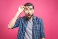 OMG! It`s incredible! Portrait of handsome young man in glasses looking at camera while standing against pink background. Close u Royalty Free Stock Photo