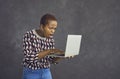 Young african american woman with shocked and surprised face looking at laptop screen. Royalty Free Stock Photo