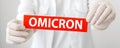 Omicron red warning sign with text new Omicron variant covid 19 in doctor hands in white coat and gloves. Long web Royalty Free Stock Photo