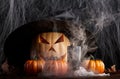 Ominous glowing halloween pumpkin with cobweb and smoke background with small pumpkins
