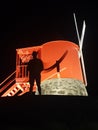 ominous night image of man silhouette under red windmill background
