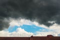 Dark rain clouds in light blue sky over roof