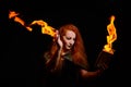 An ominous witch sets her spell book on fire with the power of thought. Red-haired woman conjures for Halloween. Flames Royalty Free Stock Photo