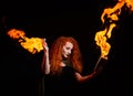 An ominous witch sets her spell book on fire with the power of thought. Red-haired woman conjures for Halloween. Flames Royalty Free Stock Photo