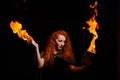 An ominous witch sets her spell book on fire with the power of thought. Red-haired woman conjures for Halloween. Flames Royalty Free Stock Photo