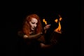 An ominous witch sets her spell book on fire with the power of thought. Red-haired woman conjures for Halloween. Flames Royalty Free Stock Photo