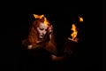 An ominous witch sets her spell book on fire with the power of thought. Red-haired woman conjures for Halloween. Flames Royalty Free Stock Photo