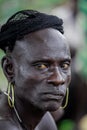 Close up Portrait of African Man with Golden Earrings and Black Net on the Head in the local Mursi tribe village