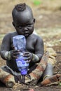 Omo River Valley, Ethiopia, November 2020, A small child from the Mursi tribe sits on the ground Royalty Free Stock Photo