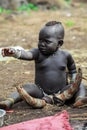 Omo River Valley, Ethiopia, November 2020, A small child from the Mursi tribe sits on the ground Royalty Free Stock Photo