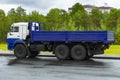 An onboard lorry with an elongated blue body and white cab stands on road in city in Siberia. Side view.