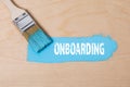 ONBOARDING. Paint brush with blue paint on a wooden surface