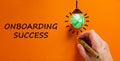 Onboarding success symbol. Businessman writing words `onboarding success`, isolated on beautiful orange background. Light bulb