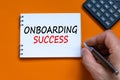 Onboarding success symbol. Businessman writing words Onboarding success on white note. Black calculator. Beautiful orange