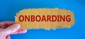 Onboarding symbol. The concept word `onboarding` on the piece of cardboard between fingers. Beautiful blue background, copy spac