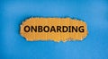 The concept word \'onboarding\' on piece of cardboard. Beautiful blue background copy space. Business and