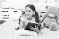 Once upon a time. Girl child in bed read book with teddy bear plush toy. Pleasant time in cozy bedroom. Girl kid long Royalty Free Stock Photo