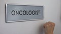 Oncologist room door, patient hand knocking closeup, cancer risk prevention