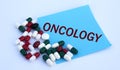 ONCOLOGY word on a blue sheet of paper against the background of multicolored tablets Royalty Free Stock Photo