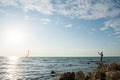 One active male playing with flying kite standing on sea rocky coast on sunset summer leisure activity Royalty Free Stock Photo