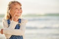 One adorable little girl thinking of ideas while standing on a beach outdoors. A cute young kid looking thoughtful while Royalty Free Stock Photo