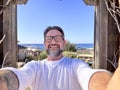 One adult happy man taking selfie picture with camera phone in outdoor leisure activity with beach bar and ocean in background. Royalty Free Stock Photo