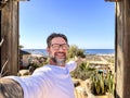 One adult happy man taking selfie picture with camera phone in outdoor leisure activity with beach bar and ocean in background. Royalty Free Stock Photo