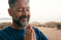 One adult man praying and meditate outdoor in relaxation gesture with hands clasped and closed eyes portrait. Zen like healthy Royalty Free Stock Photo