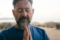 One adult man praying and meditate outdoor in relaxation gesture with hands clasped and closed eyes portrait. Zen like healthy