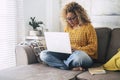 One adult modern woman at home working on laptop alone sitting on the sofa inside apartment, Indoor technology leisure activity Royalty Free Stock Photo