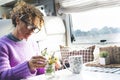 One adult woman caring plants and flowers inside a camper van modern tiny house motorhome rv alone. People living vanlife fulltime