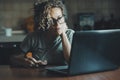 One adult woman using computer in early morning at home drinking an espresso coffee. Female people watching laptop with attention Royalty Free Stock Photo