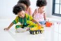 One African mixed race boy is playing with truck toys in front of the other girls and look enjoy and happy with this activity