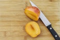 One Amigo Pluot Cut Open with a Knife on a Wood Chopping Board