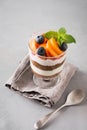 One apricot trifle, chocolate biscuit, layered dessert with fresh berry and gentle cream cheese on grey background. Selective Royalty Free Stock Photo