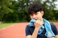 One Asia male Athlete use towel wipe face and Drinking Water Bottle on the Track with copy space