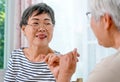 One Asian elderly woman hook each others little finger to the other with smiling in front of balcony in the house