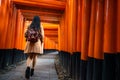 One Asian woman traveller with backpack walking and sightseeing at famous destination Fushimi Inari Shrine in Kyoto, Japan. Japan