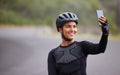 One athletic young woman taking a selfie using her smartphone during a break from cycling outside. Sporty fit mixed race Royalty Free Stock Photo