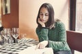 One attractive young lady sat at a table reading the menu in a bistro restaurant on her own Royalty Free Stock Photo