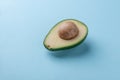 One avocado half with kernel on blue background Royalty Free Stock Photo