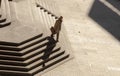 One bald man in suit and coat carrying briefcase walking alone down the huge public stairs