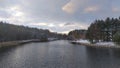 One bank of the river is concreted, there are reeds near the other. There is a forest growing on the banks. The first snow that ha Royalty Free Stock Photo