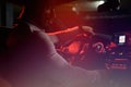 cute bearded strong young man in white shirt sitting in luxury sport muscle car lit with red light in underground garage Royalty Free Stock Photo