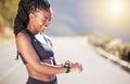 One beautiful african american female athlete checking her smartwatch while exercising outdoors. A young athletic woman Royalty Free Stock Photo